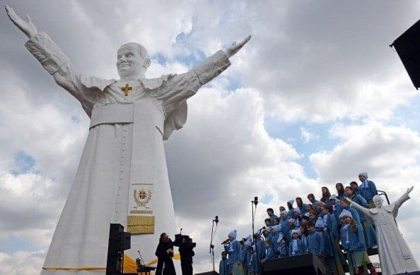 A children's choir is pictured as a child sings next to the 13,8 m tall sculpture of late Pope John Paul II and a small replica after the unveiling ceremony in Czestochowa, southern Poland, on April 13, 2013. The world's tallest statue of late pope John Paul II was unveiled Saturday in the Polish city of Czestochowa, already home to a Catholic icon believed to work miracles. AFP PHOTO/JANEK SKARZYNSKI        (Photo credit should read JANEK SKARZYNSKI/AFP/Getty Images)