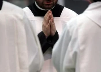 prete in preghiera con le mani giunte